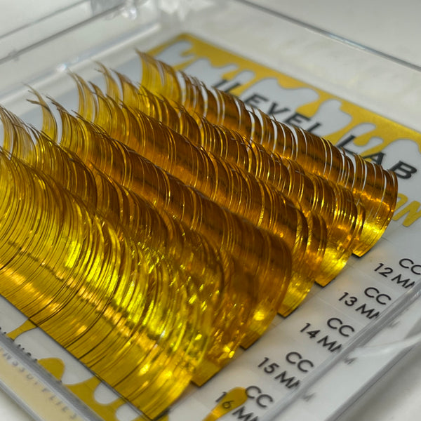 alt="Gold tinsel holographic lash extensions in mixed length tray for professional lash extension application"
